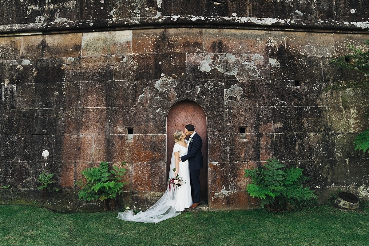 Bride and Groom infront of the red stone wall and red door at Gunners Barracks